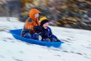 photo of kids sliding down hill in snow